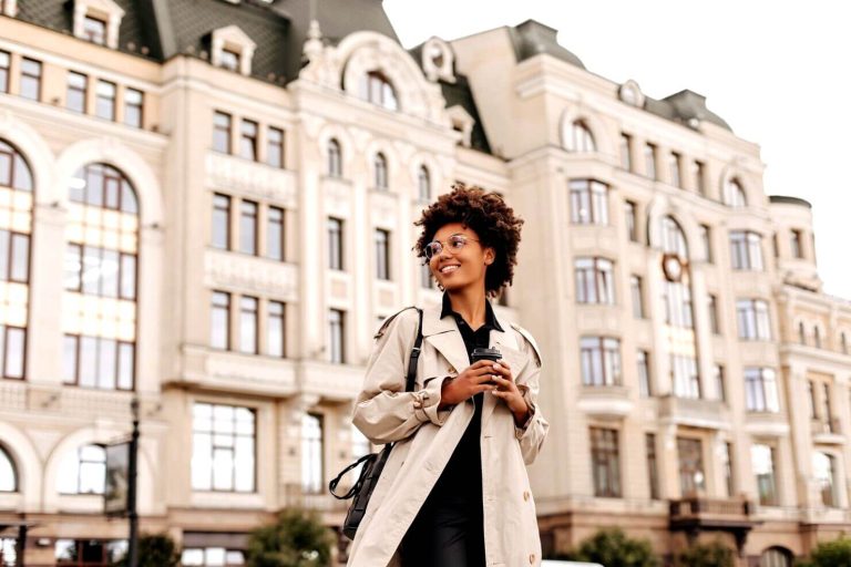 Jolie jeune femme brune heureuse devant un bâtiment à Paris